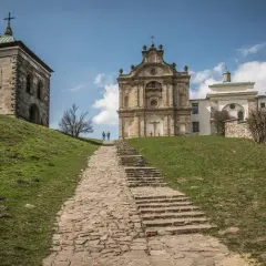 Kamienna ścieżka prowadzi na szczyt łysy góra do barokowego klasztoru i wieży. Dwie postacie wędrują w górę.