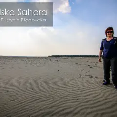 Kobieta stoi na piaszczystym terenie, który przypomina pustynię. To polska Sahara, czyli Pustynia Błędowska.