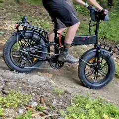 Rowerzysta na rowerze elektrycznym z grubymi oponami przemierza leśną ścieżkę, jakby to była ścieżka rowerowa Władysławowo Hel.
