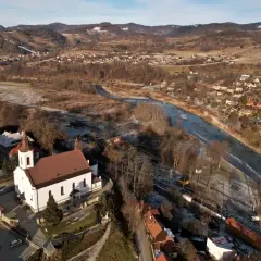 Zimowy krajobraz doliny Popradu z kościołem, rzeką i zabudowaniami.