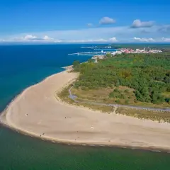 Plaża i las na Helu, końcu Polski. Woda, piasek i zielone drzewa tworzą malowniczy krajobraz.