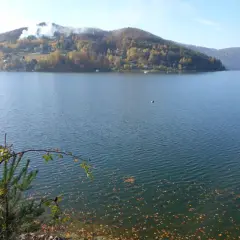 Jesioro Rożnowskie w jesiennej odsłonie. Woda spokojna, na wzgórzach złote liście, a na niebie błękit.