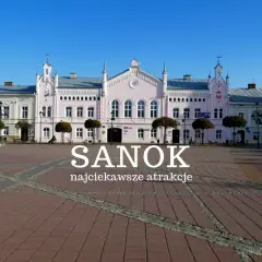 Rynek w Sanoku z pastelowymi kamieniczkami i napisem "Sanok najciekawsze atrakcje". Idealne miejsce na odkrywanie atrakcji Sanoka i okolic.