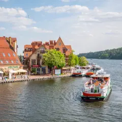 Malowniczy widok na port z łodziami i kamiennymi budynkami. Wspaniałe mikołajki atrakcje czekają na turystów nad jeziorem.