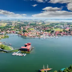 Malownicze miasteczko nad jeziorem, prawdziwa kraina tysiąca jezior. Widok na port z łodziami i żaglówkami, czerwone dachy domów i błękitne niebo.
