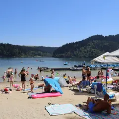 Słoneczna czorsztyn plaża tętni życiem. Ludzie kąpią się, opalają i relaksują nad jeziorem, otoczonym zielonymi wzgórzami.