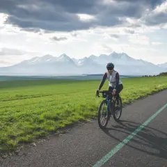 Kobieta na rowerze pokonuje malowniczą trasę z widokiem na ośnieżone Tatry. To wyzwanie: rowerem dookoła Tatr w jeden dzień!