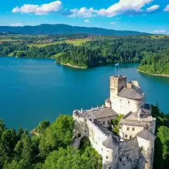 Zamek w Niedzicy góruje nad turkusowym zalewem czorsztyńskim, otoczony zielonymi lasami i pagórkami.