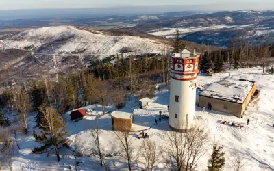 Wieża widokowa na Biskupiej Kopie w zimowej scenerii. Śnieg pokrywa okoliczne wzgórza i lasy.