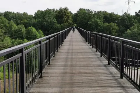 Rowerzysta na drewnianym moście wśród drzew. Idealne miejsce na odkrywanie tras rowerowych Bydgoszcz.