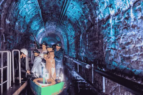 Podziemna łódź w kopalni, jedna z gliwickich atrakcji, zabiera turystów w podróż przez oświetlony na niebiesko tunel.