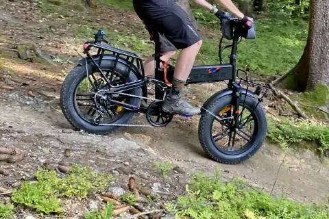 Rowerzysta na rowerze elektrycznym z grubymi oponami przemierza leśną ścieżkę, jakby to była ścieżka rowerowa Władysławowo Hel.