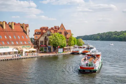 Malowniczy widok na port z łodziami i kamiennymi budynkami. Wspaniałe mikołajki atrakcje czekają na turystów nad jeziorem.