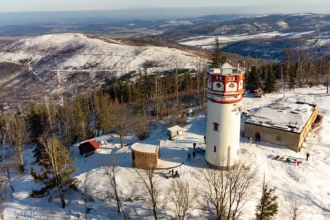 Wieża widokowa na Biskupiej Kopie w zimowej scenerii. Śnieg pokrywa okoliczne wzgórza i lasy.