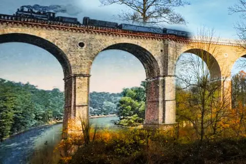 Historyczny most kolejowy w Zgorzelcu, z parowozem na tle jesiennego krajobrazu.