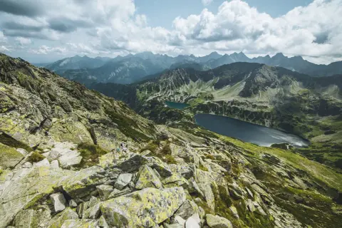 Widok z Kozi Wierch na Tatry. Skaliste zbocza, zielone doliny i dwa jeziora.