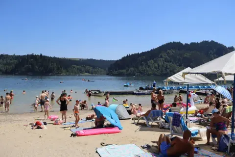 Słoneczna czorsztyn plaża tętni życiem. Ludzie kąpią się, opalają i relaksują nad jeziorem, otoczonym zielonymi wzgórzami.