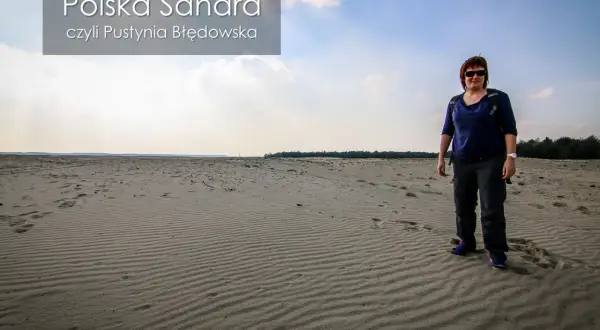 Kobieta stoi na piaszczystym terenie, który przypomina pustynię. To polska Sahara, czyli Pustynia Błędowska.