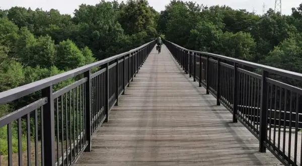 Rowerzysta na drewnianym moście wśród drzew. Idealne miejsce na odkrywanie tras rowerowych Bydgoszcz.