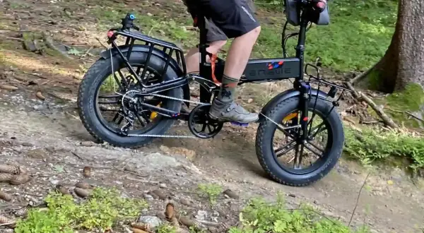 Rowerzysta na rowerze elektrycznym z grubymi oponami przemierza leśną ścieżkę, jakby to była ścieżka rowerowa Władysławowo Hel.