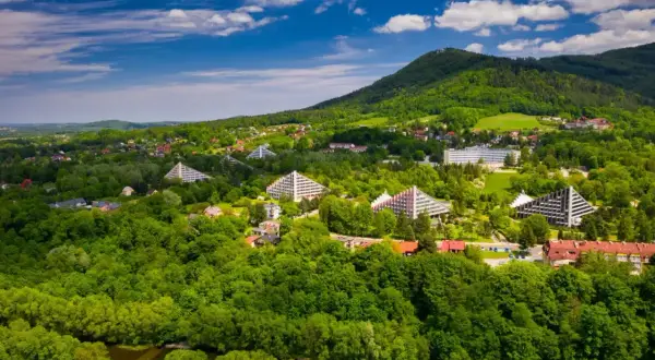 Ustroń atrakcje: widok z lotu ptaka na zielone wzgórza, rzekę i charakterystyczne budynki w kształcie piramid.