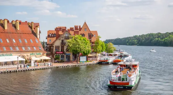 Malowniczy widok na port z łodziami i kamiennymi budynkami. Wspaniałe mikołajki atrakcje czekają na turystów nad jeziorem.