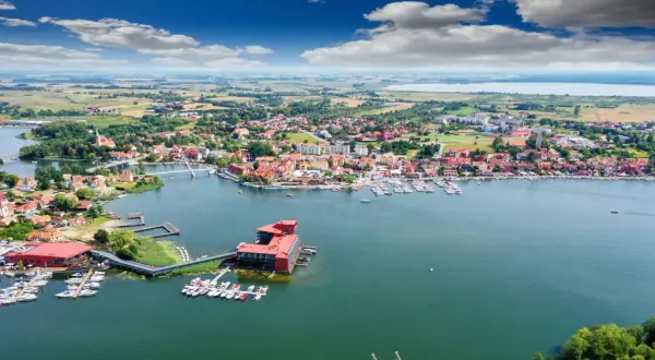 Malownicze miasteczko nad jeziorem, prawdziwa kraina tysiąca jezior. Widok na port z łodziami i żaglówkami, czerwone dachy domów i błękitne niebo.