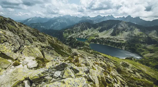 Widok z Kozi Wierch na Tatry. Skaliste zbocza, zielone doliny i dwa jeziora.