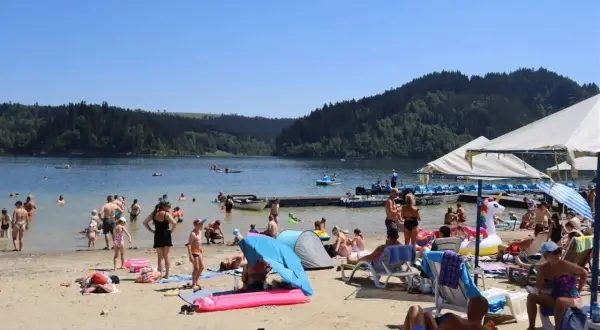 Słoneczna czorsztyn plaża tętni życiem. Ludzie kąpią się, opalają i relaksują nad jeziorem, otoczonym zielonymi wzgórzami.