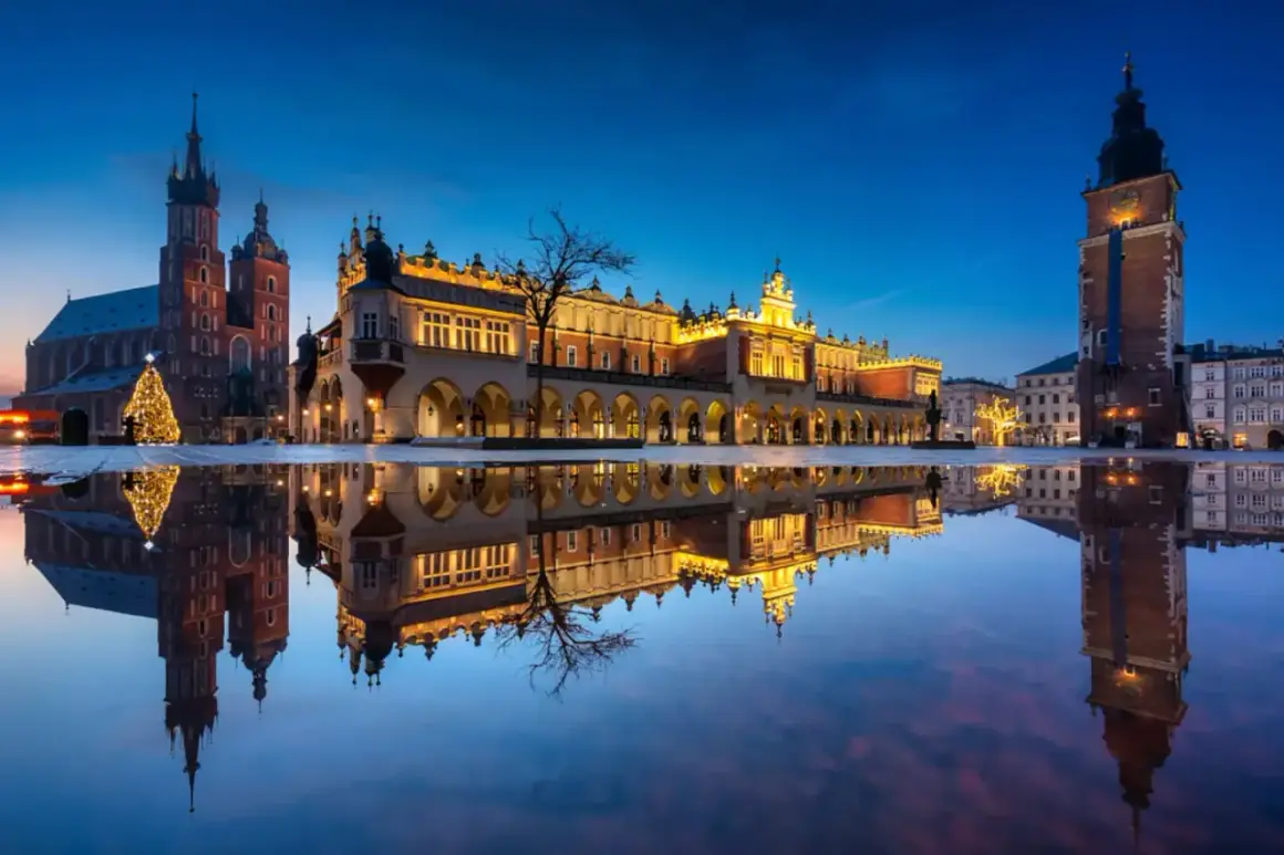 Wieczorny Rynek Główny w Krakowie z odbiciem w kałuży. Zobacz, co można robić w Krakowie: zwiedzać Sukiennice, Kościół Mariacki i podziwiać iluminacje.
