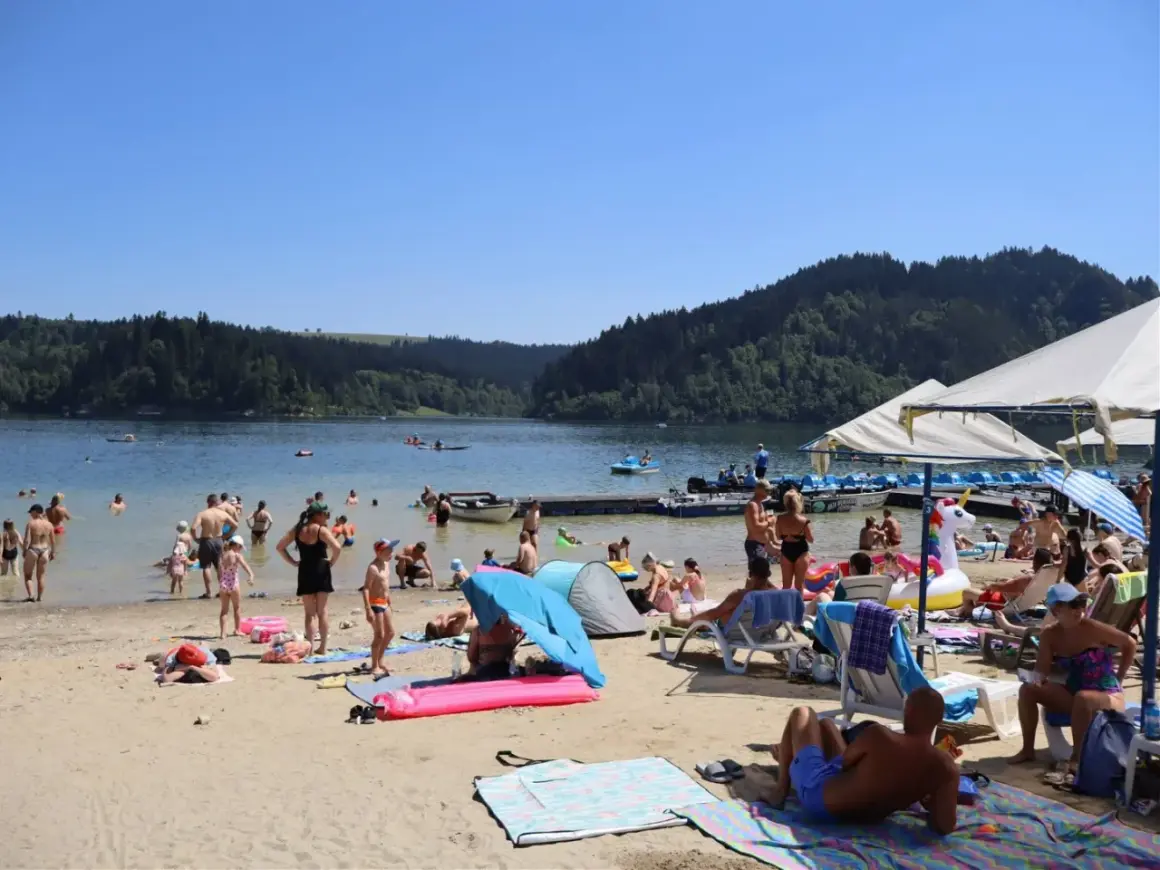Słoneczna czorsztyn plaża tętni życiem. Ludzie kąpią się, opalają i relaksują nad jeziorem, otoczonym zielonymi wzgórzami.