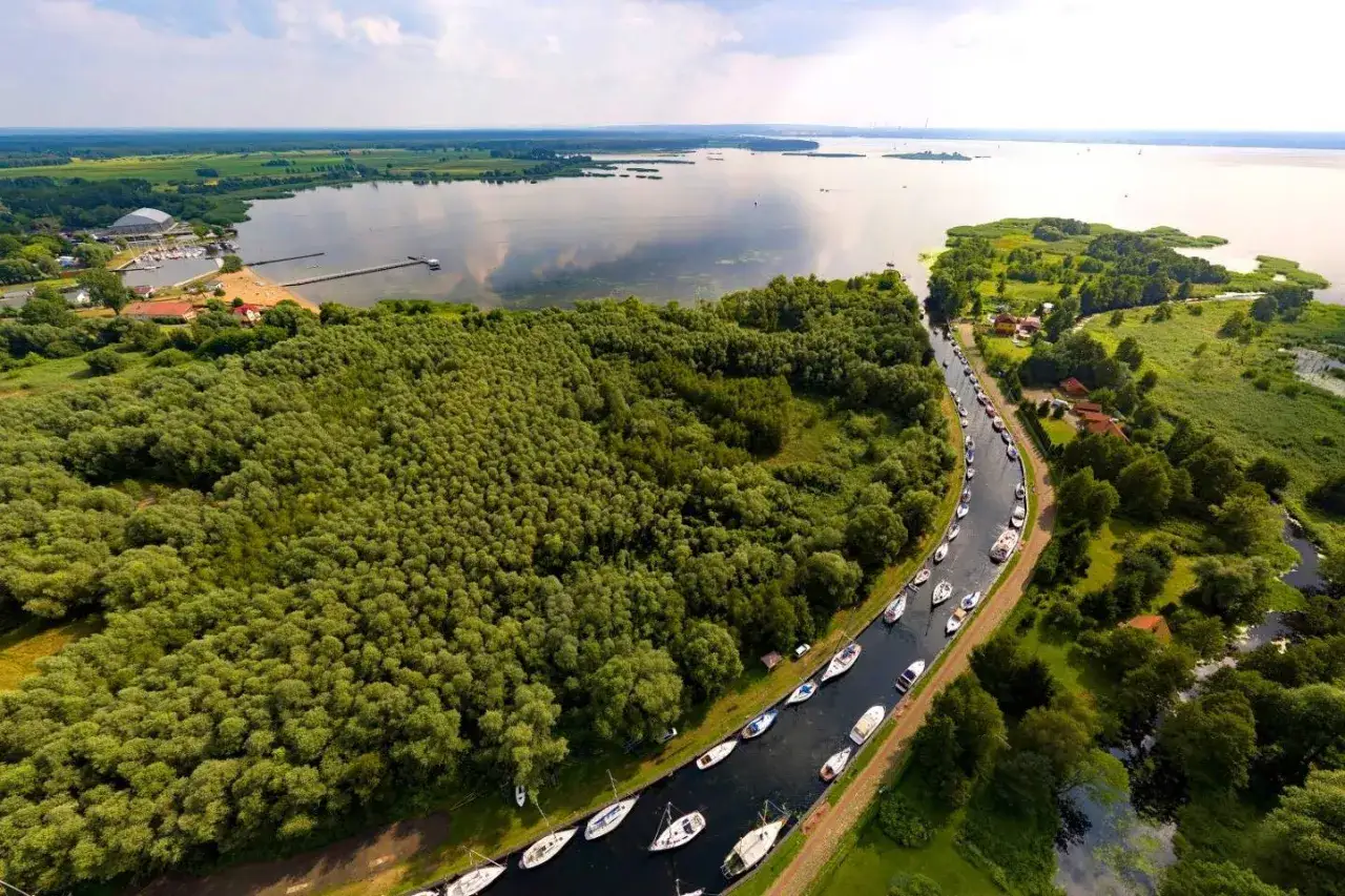 Malowniczy widok na Zalew Szczeciński z licznymi żaglówkami cumującymi w kanale i na otwartych wodach.