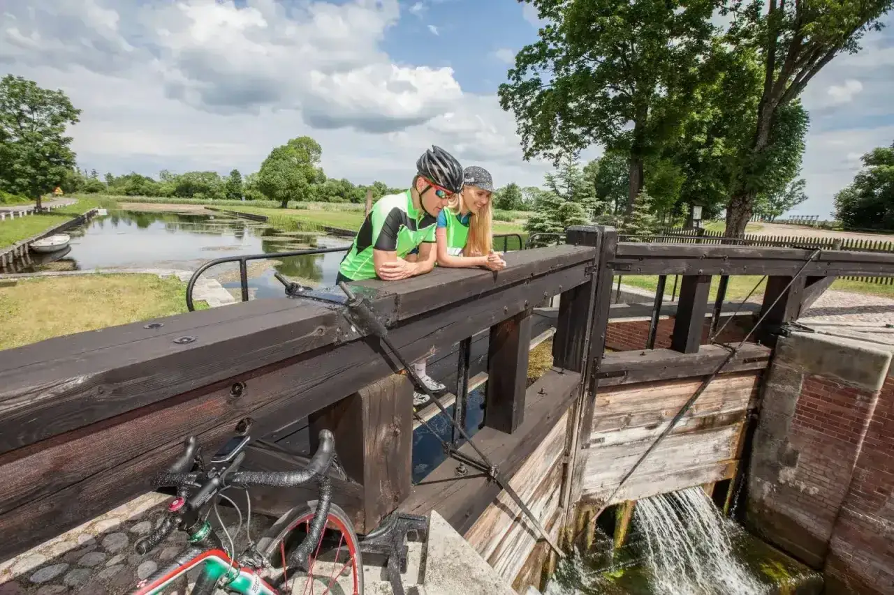Para rowerzystów odpoczywa przy śluzie, podziwiając malownicze trasy rowerowe Augustów.