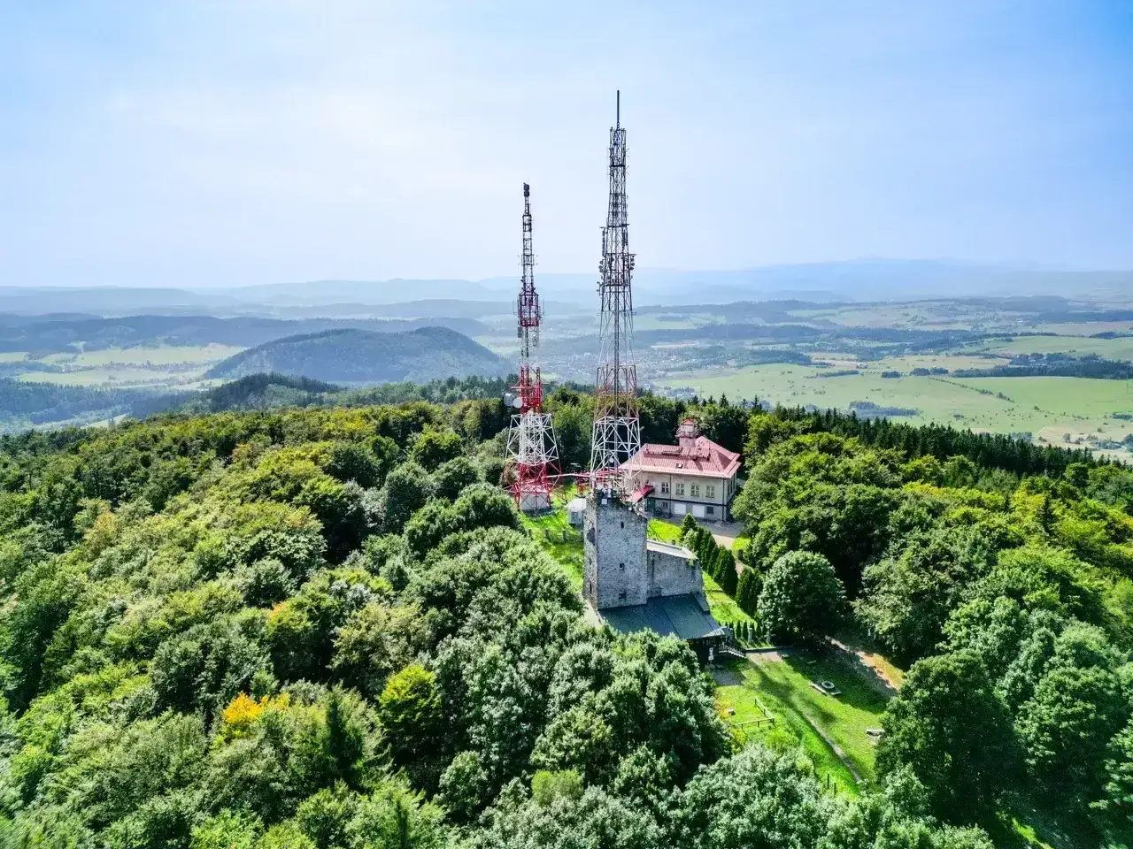 Wieże telekomunikacyjne na zalesionym chełmiec szczyt górują nad krajobrazem.