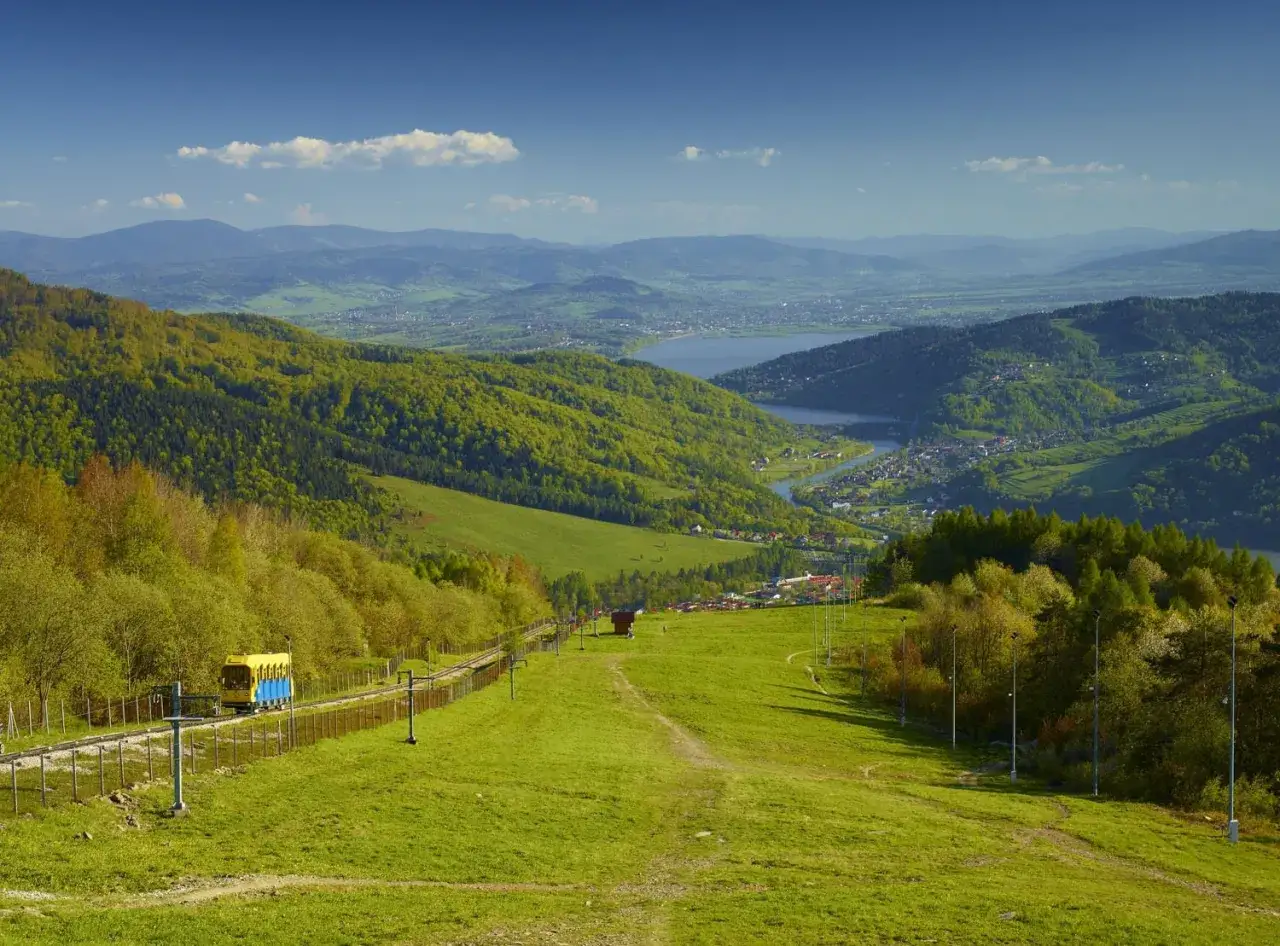 Widok na Beskid Mały z kolejką górską i jeziorem w oddali.
