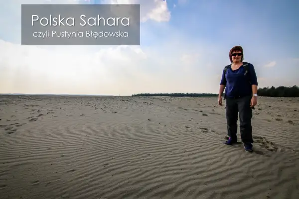 Kobieta stoi na piaszczystym terenie, który przypomina pustynię. To polska Sahara, czyli Pustynia Błędowska.