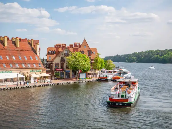 Malowniczy widok na port z łodziami i kamiennymi budynkami. Wspaniałe mikołajki atrakcje czekają na turystów nad jeziorem.