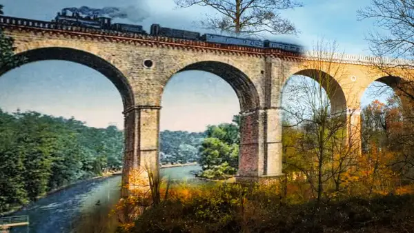 Historyczny most kolejowy w Zgorzelcu, z parowozem na tle jesiennego krajobrazu.