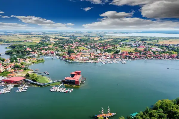 Malownicze miasteczko nad jeziorem, prawdziwa kraina tysiąca jezior. Widok na port z łodziami i żaglówkami, czerwone dachy domów i błękitne niebo.