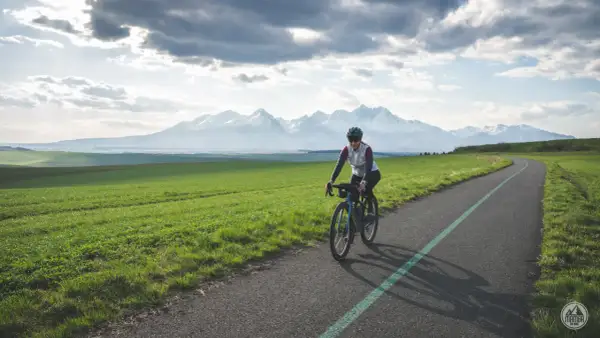 Kobieta na rowerze pokonuje malowniczą trasę z widokiem na ośnieżone Tatry. To wyzwanie: rowerem dookoła Tatr w jeden dzień!